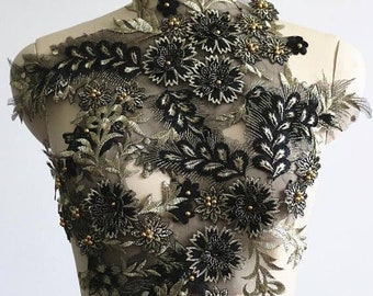 May include: Black and gold floral applique with 3D flowers and leaves. The applique is made of lace and is perfect for adding a touch of elegance to any garment.