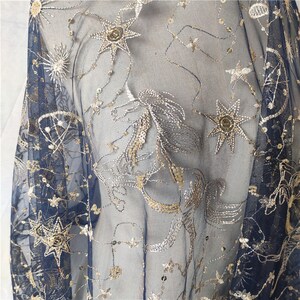 May include: Navy blue sheer fabric with gold and silver embroidered stars and constellations. The fabric is delicate and has a soft, flowing texture.
