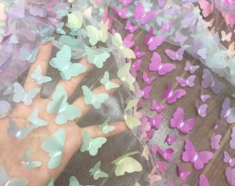 May include: A sheer fabric with a rainbow ombre effect and a repeating pattern of iridescent butterflies.