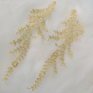 以下が含まれることがあります： 繊細な葉と花のデザインが施された、ゴールドのフローラルレースアップリケ2つ。アップリケは、どんなプロジェクトにもエレガントなタッチを加えるのに最適です。