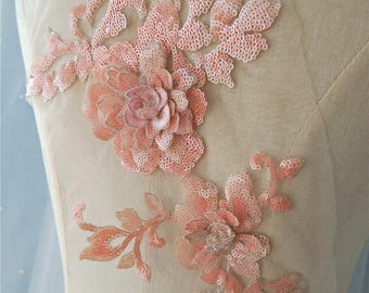 May include: Peach-colored floral applique with sequins and beads. The applique features two large flowers and delicate leaves. This embellishment is perfect for adding a touch of elegance to clothing, accessories, or home decor projects.