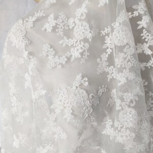 May include: White sheer fabric with delicate floral embroidery. The fabric is lightweight and translucent, with a soft, flowing texture.