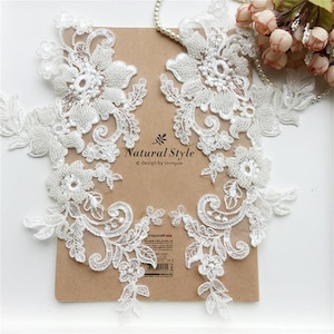 May include: Two white lace appliques with pearl beading and floral designs. The appliques are on a brown paper background with the text "Natural Style © design by longuo".