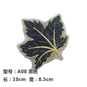 May include: Black and gold embroidered leaf applique. The leaf design is detailed with gold stitching on a black background. The applique measures approximately 4 inches long by 3.3 inches wide.