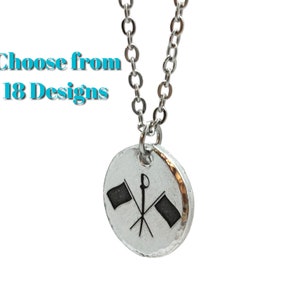 May include: Silver necklace with a round pendant featuring a black and white illustration of two crossed flags and a baton.  Choose from 18 designs.