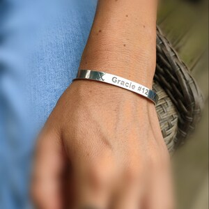 May include: Silver bracelet inscribed with "Gracie #12" and a hockey stick design.