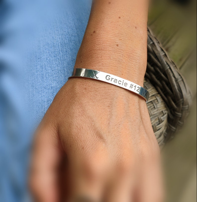 May include: Silver bracelet inscribed with "Gracie #12" and a hockey stick design.
