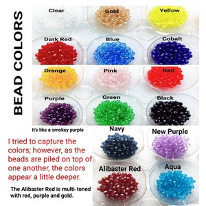 May include: A chart of 16 different colours of beads, each colour is labelled with its name. The beads are arranged in a grid of four rows and four columns. The colours are: Clear, Gold, Yellow, Dark Red, Blue, Cobalt, Orange, Pink, Red, Purple, Green, Black, Navy, New Purple, Alibaster Red, and Aqua.