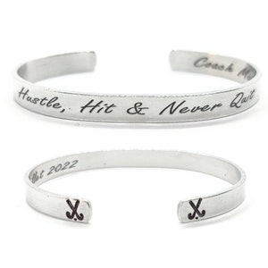 May include: Silver bracelet inscribed with "Hustle, Hit & Never Quit" and a hockey stick symbol on each end.