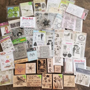 May include: A collection of rubber stamps featuring various designs and phrases. The stamps are arranged on a wooden surface. Some of the phrases include "Special Thank You", "Hello", "Live the Life You've Imagined", and "On Your Wedding Day".