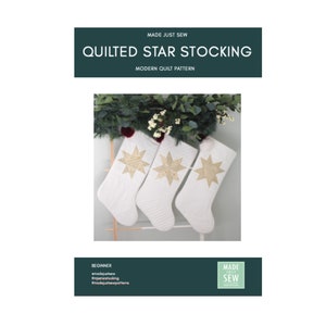 May include: Three white quilted Christmas stockings with gold star designs hanging on a wooden rack. The stockings are decorated with white pom-poms. The text "MADE JUST SEW" and "QUILTED STAR STOCKING" is visible at the top of the image.