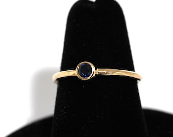 May include: A gold ring with a single blue gemstone set in the center.