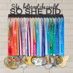 Appendi medaglie personalizzato: Espositore in acciaio inox nero con scritta « She Believed »