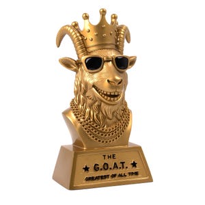 Può includere: Un trofeo dorato raffigurante una testa di capra con occhiali da sole e una corona. La capra indossa una collana d'oro e sorride. La base del trofeo recita "THE G.O.A.T. GREATEST OF ALL TIME."
