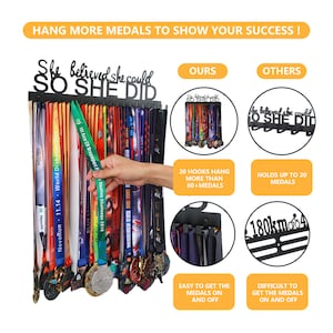 Puede incluir: Expositor de medallas de metal negro con el texto "She believed she could so she did". El soporte tiene 20 ganchos y puede contener m&aacute;s de 60 medallas. El soporte se muestra con una variedad de medallas coloridas colgadas.