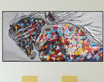May include: A colorful abstract painting of two horses' heads with white manes against a gray background. The painting is framed and hanging on a white wall above a glass table with yellow chairs.