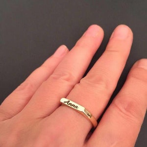 Puede incluir: Un anillo de banda de oro con el nombre "Anna" grabado en él.