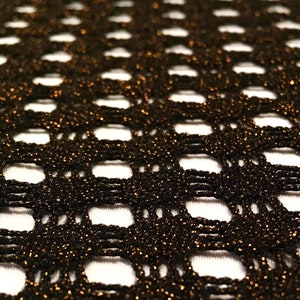 May include: Black mesh fabric with a subtle gold shimmer. The fabric has a diamond-shaped pattern.