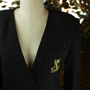 May include: A black blazer with a gold anchor pin on the left pocket.
