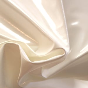 May include: Close-up of a white, shiny, and smooth fabric with a soft, flowing texture. The fabric is folded and draped, creating a luxurious and elegant look.