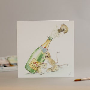 Peut inclure: Une illustration à l'aquarelle d'une bouteille de champagne ouverte par un groupe de souris. La bouteille est étiquetée "Prosecco" et les souris ont toutes des expressions différentes.