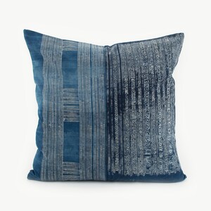 May include: A blue and white patterned throw pillow with a geometric design. The pillow is made of a soft, textured fabric.