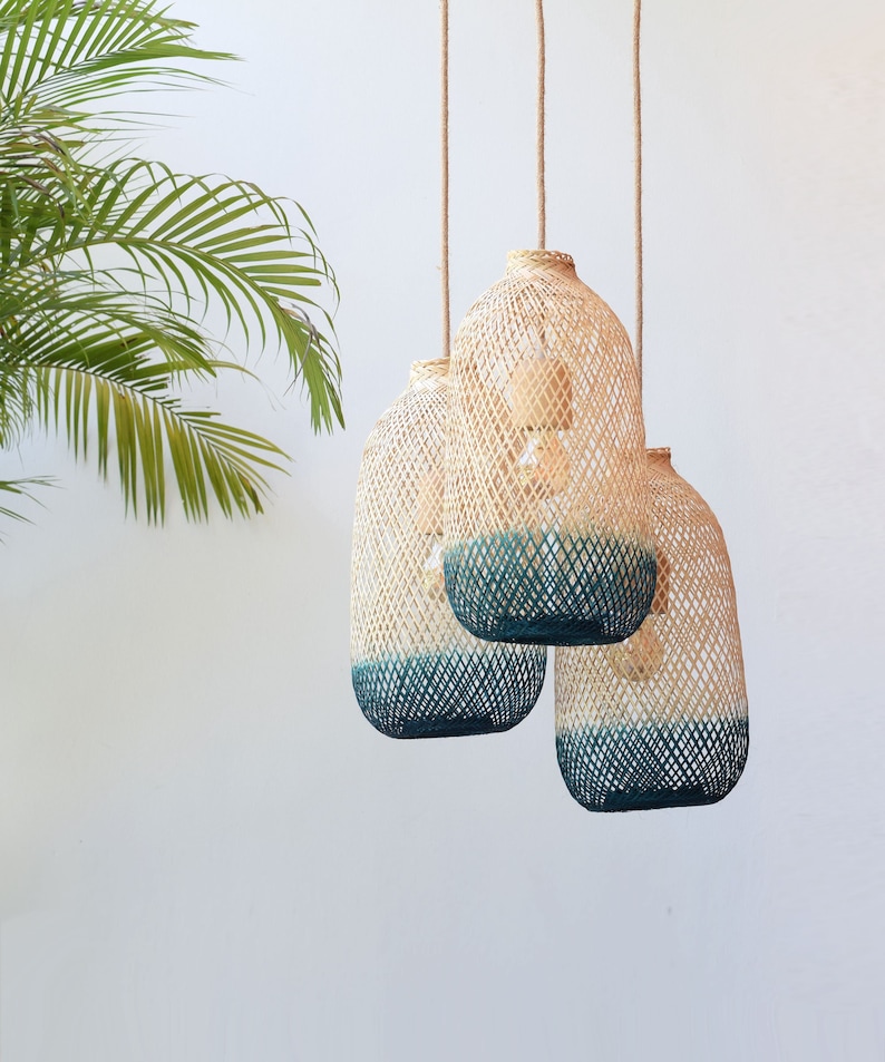 May include: Three woven pendant lights with a teal blue ombre effect. The lights are hanging from a white ceiling.