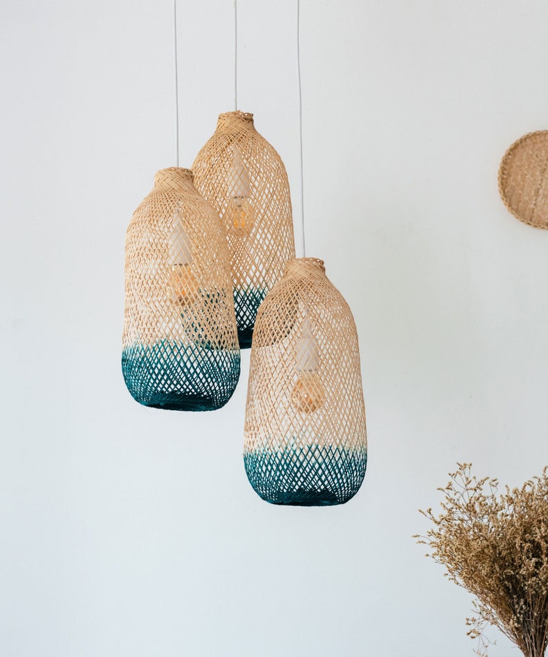 May include: Three woven pendant lights with a blue ombre finish. The lights are hanging from the ceiling and are made of natural materials.