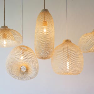 May include: Five woven pendant lights with warm white bulbs hanging from the ceiling. The lights are made of natural materials and have a rustic, bohemian style.