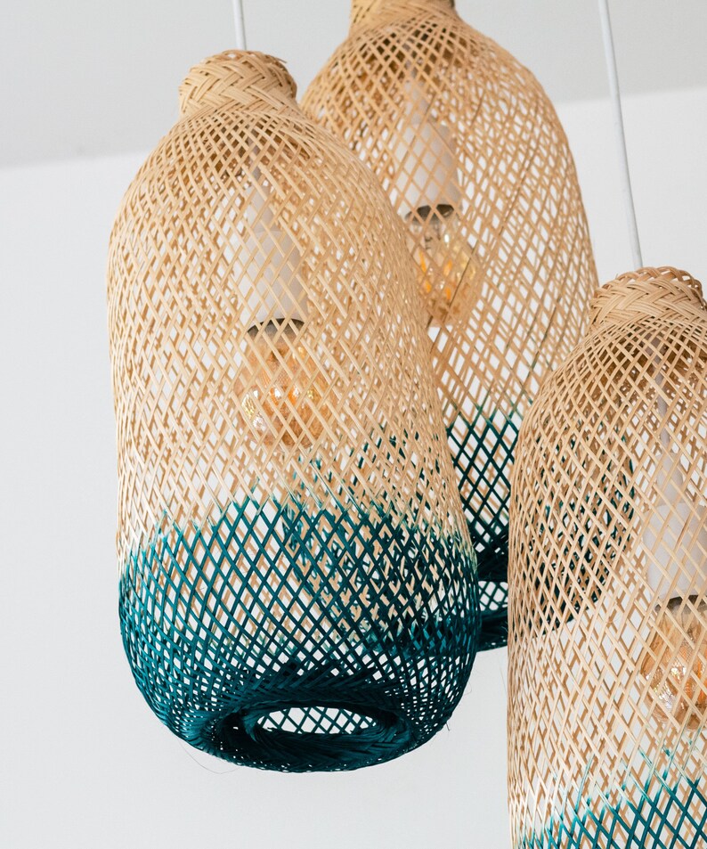 May include: Three woven pendant lights with a teal ombre effect. The lights are made of natural materials and have a rustic, bohemian style.