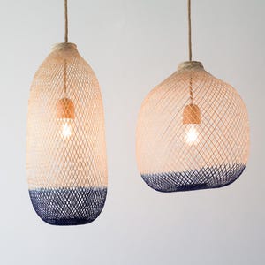 May include: Two hanging pendant lights with woven rattan shades. The shades are a light beige color with a dark blue band around the bottom.