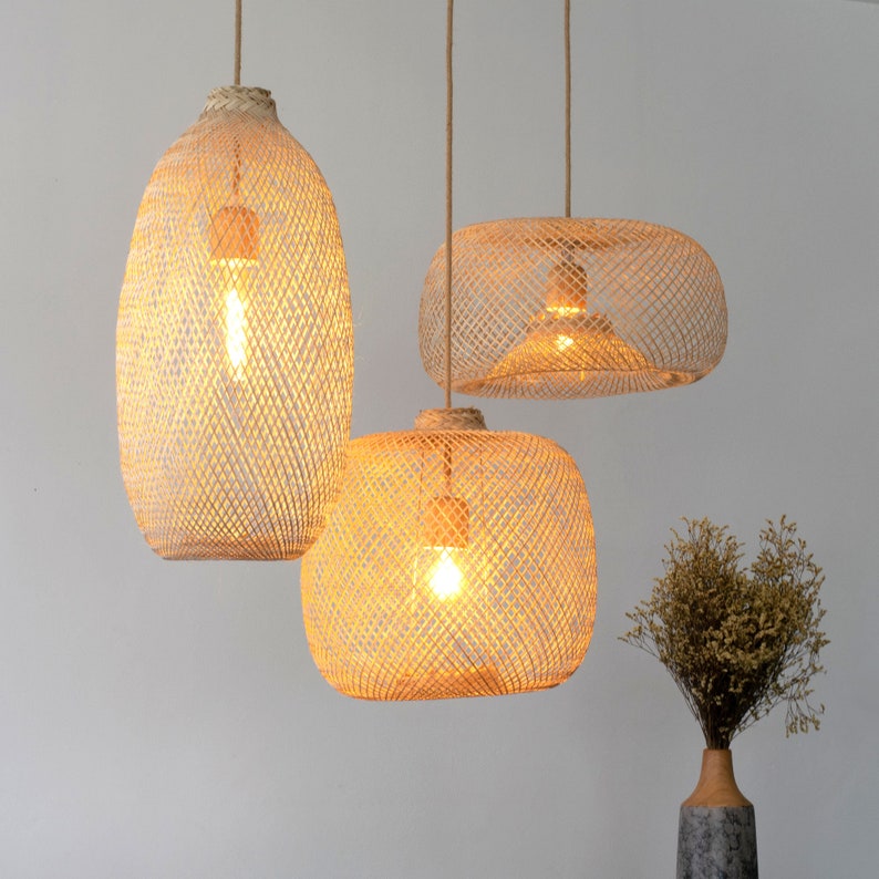 Pu&ograve; includere: Tre luci a sospensione in bamb&ugrave; intrecciato con lampadine a luce bianca calda appese al soffitto.