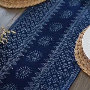 May include: A blue table runner with a white geometric pattern. The runner is made of cotton and has a woven texture. It is a great way to add a touch of style to your dining table.