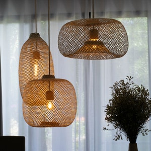 Pu&ograve; includere: Tre luci a sospensione intrecciate con lampadine a luce bianca calda appese a un soffitto bianco su uno sfondo di tende bianche trasparenti.