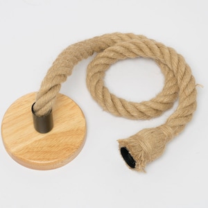 Puede incluir: Una lámpara colgante de cuerda marrón claro. La lámpara presenta un diseño de cuerda trenzada gruesa con una base de madera y un casquillo negro. La cuerda está en bucle y parece estar hecha de fibras naturales.