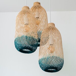 May include: Three woven pendant lights with a teal ombre design. The lights are made of natural materials and have a rustic, bohemian style.