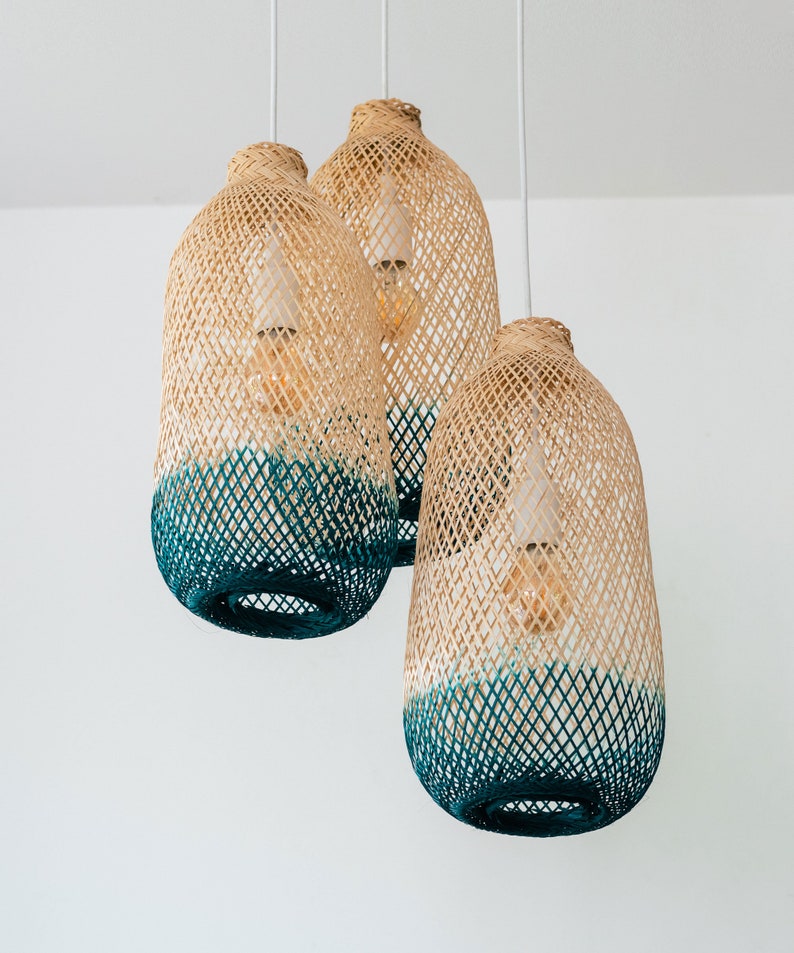 May include: Three woven pendant lights with a teal ombre design. The lights are made of natural materials and have a rustic, bohemian style.