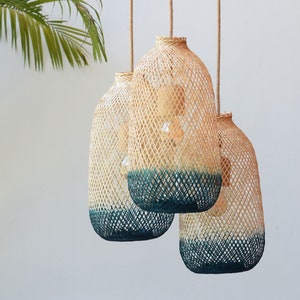 May include: Three woven pendant lights with a teal blue ombre effect. The lights are made of natural materials and have a rustic, bohemian style.