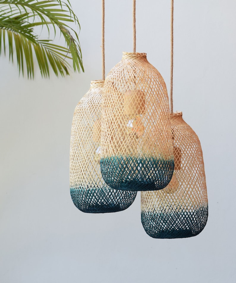 May include: Three woven pendant lights with a teal blue ombre effect. The lights are made of natural materials and have a rustic, bohemian style.