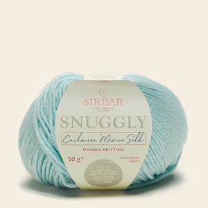 May include: A ball of light blue yarn labeled "Sirdar Snuggly Cashmere Merino Silk Double Knitting" with a white label that says "50 g* 116 m/127 yds Approx West Yorkshire British Design Expertise and Craftsmanship Trusted by Generations of Hand Knitters."