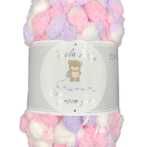 Op de afbeelding: Een bol roze, wit en lavendelkleurig gigantisch pompon garen. Het garen is verpakt met een label waarop "Zarela Baby Giant Pom Pom Yarn" staat en een cartoonbeer is afgebeeld.