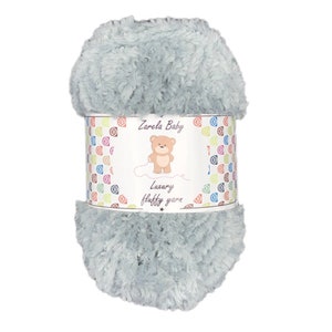 May include: A skein of light blue fluffy yarn with a label that reads "Zarela Baby Luxury fluffy yarn" and features a cartoon teddy bear.