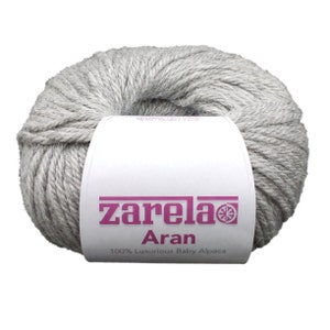 May include: A skein of light gray yarn labeled "zarela Aran 100% Luxurious Baby Alpaca".