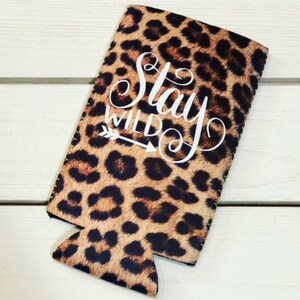 May include: Leopard print can cooler with the text "Stay Wild" in white lettering and an arrow pointing to the right.