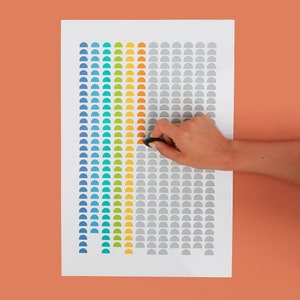 May include: A white sheet of paper with a grid of colorful semi-circles. The semi-circles are arranged in a rainbow pattern, with blue, turquoise, green, yellow, orange, and red. The grid is divided into three sections, with the left section containing the rainbow pattern, the middle section containing a solid orange color, and the right section containing a gray color.