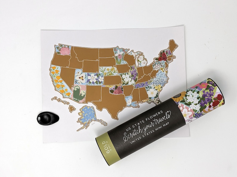 May include: A gold scratch-off map of the United States with each state featuring a different flower. The map is rolled up in a black tube with the text "US State Flowers Scratch your travels United States Mini Map" printed on it.