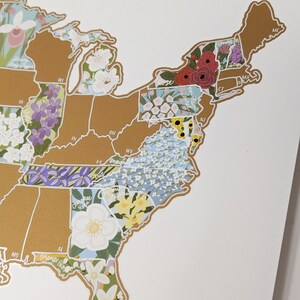 May include: A gold-toned map of the United States with each state filled with a different floral pattern. The states are outlined in white. The map is on a white background.