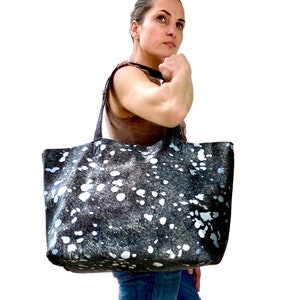 May include: A large black and white tote bag with a spotted pattern. The bag has two handles and is made of a soft, textured material.