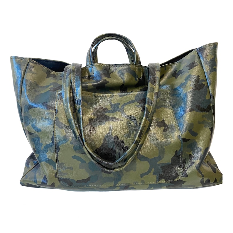 May include: A large tote bag with a camouflage pattern in shades of green and black. The bag has two handles and a pocket on the front. The material appears to be leather.