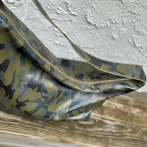 May include: A green, black, and blue camouflage leather shoulder bag with a gold zipper.